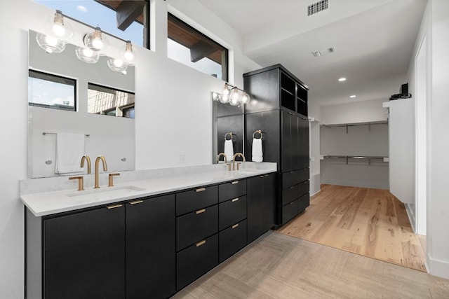 full bath featuring visible vents, a sink, wood finished floors, and double vanity