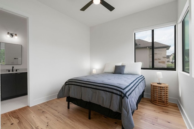 bedroom with a sink, light wood finished floors, and multiple windows