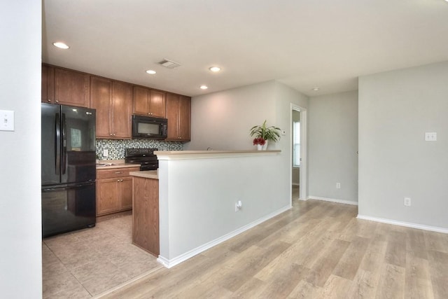 2206 Weiss Ln, Georgetown, TX 78626 - kitchen with black appliances, tasteful backsplash, baseboards, light wood-type flooring, and light countertops