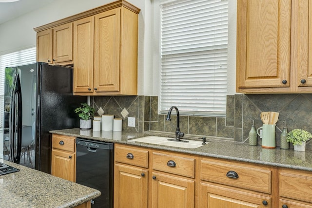 kitchen with light stone countertops, decorative backsplash, a sink, and black appliances