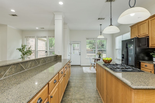 kitchen with plenty of natural light, light stone countertops, black appliances, and visible vents