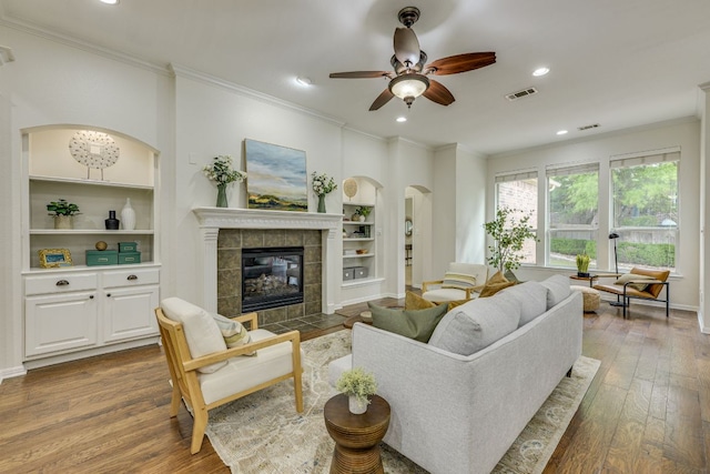 2408 Tivoli Dr, Cedar Park, TX 78613 - living room featuring ornamental molding, built in features, wood-type flooring, ceiling fan, and a tiled fireplace