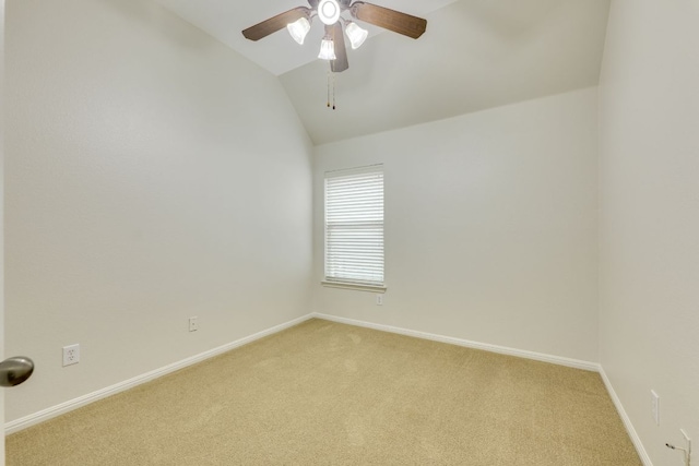 spare room with ceiling fan, light colored carpet, baseboards, and vaulted ceiling