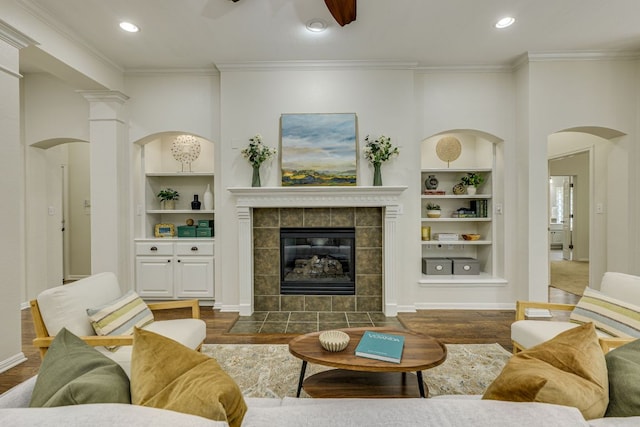 living area featuring built in shelves, ornamental molding, and wood finished floors