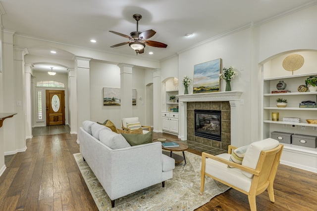 living area featuring ornamental molding, a ceiling fan, dark wood-style floors, and built in shelves