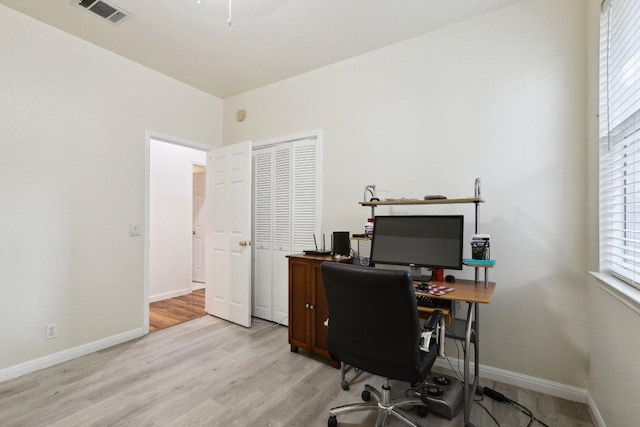 office space featuring baseboards, light wood-type flooring, and visible vents