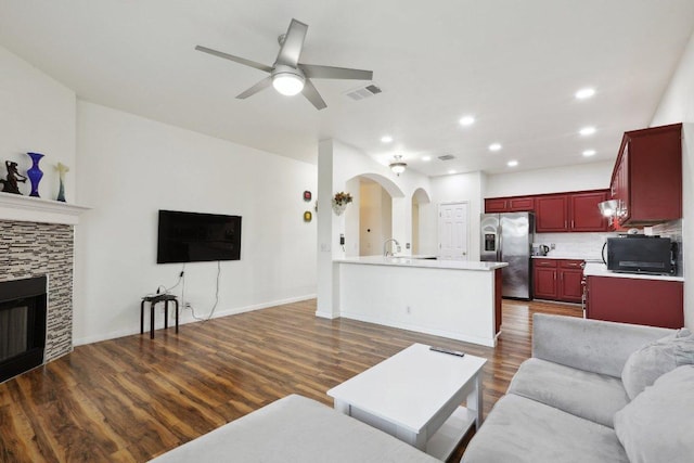 8117 Manx Dr, Round Rock, TX 78681 - living area with ceiling fan, dark wood-style flooring, arched walkways, recessed lighting, and a tiled fireplace