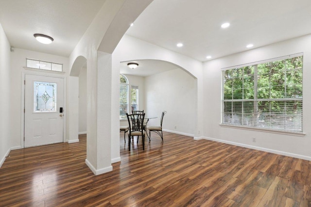 entryway featuring arched walkways, baseboards, and wood finished floors