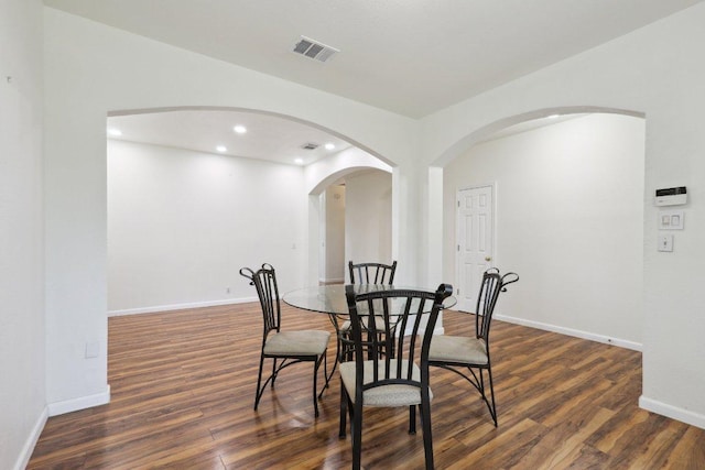 dining room featuring visible vents, arched walkways, wood finished floors, baseboards, and recessed lighting