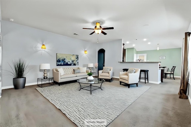 living room with ceiling fan, finished concrete floors, visible vents, arched walkways, and baseboards