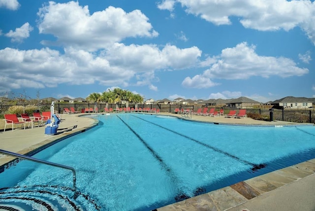 pool with a patio area, fence, and a residential view