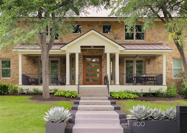 view of front of house with a standing seam roof, covered porch, and stone siding