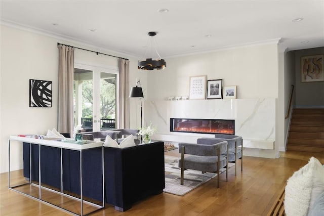 living room with crown molding, wood finished floors, a notable chandelier, and a premium fireplace