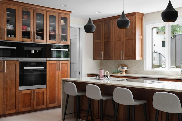 kitchen featuring a breakfast bar area, brown cabinetry, and tasteful backsplash