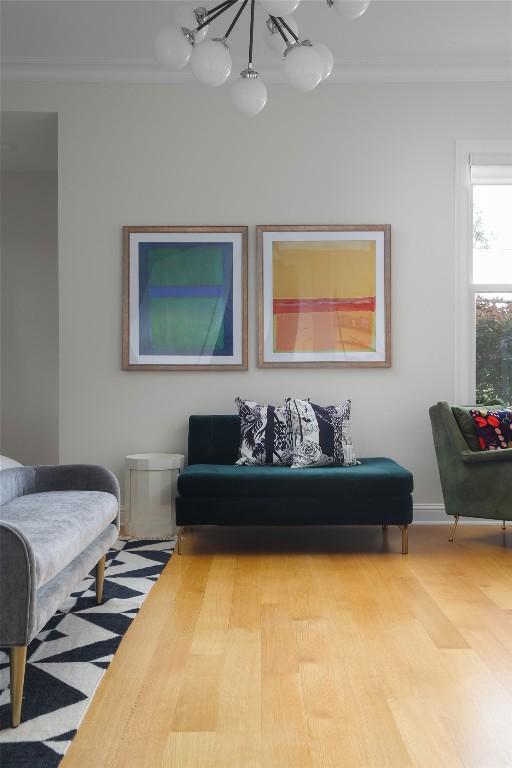 living room with baseboards, ornamental molding, and a chandelier