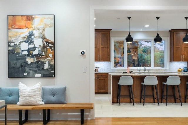 kitchen featuring light countertops, decorative backsplash, decorative light fixtures, and a kitchen bar