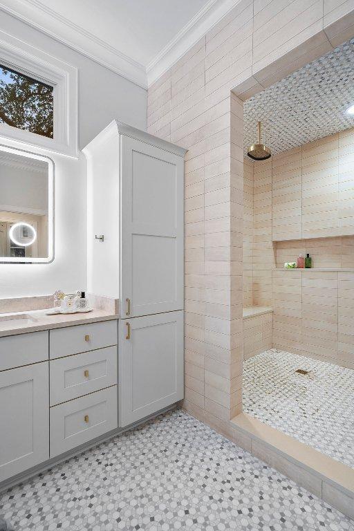 400 Almarion Dr, Austin, TX 78746 - bathroom featuring ornamental molding, a tile shower, vanity, and tile walls