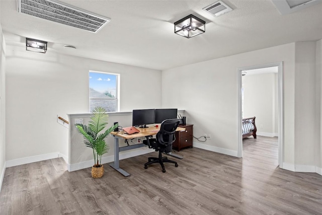home office featuring visible vents, baseboards, and wood finished floors