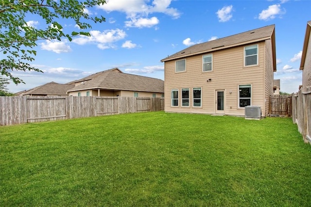 rear view of house with central air condition unit, a lawn, and a fenced backyard