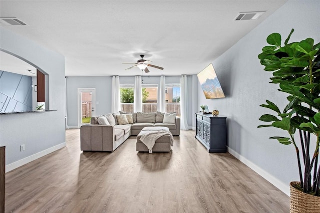 living room with arched walkways, ceiling fan, wood finished floors, and visible vents