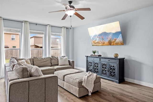 living area with baseboards, ceiling fan, and wood finished floors