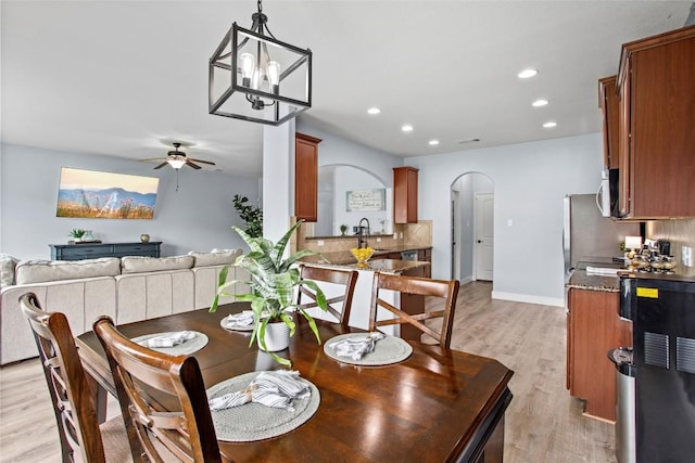 dining room with arched walkways, ceiling fan with notable chandelier, recessed lighting, light wood-type flooring, and visible vents