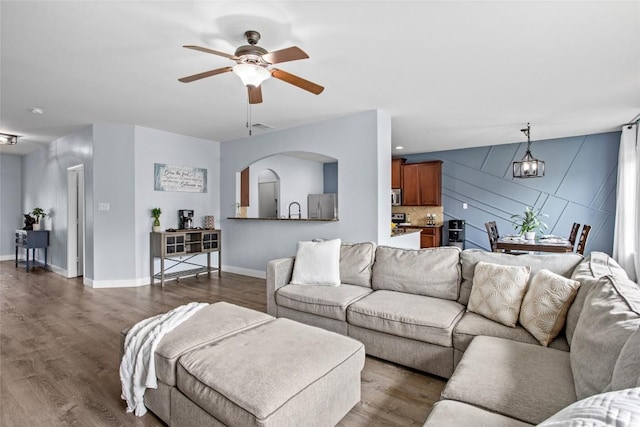 living room with baseboards, ceiling fan, visible vents, and dark wood-type flooring
