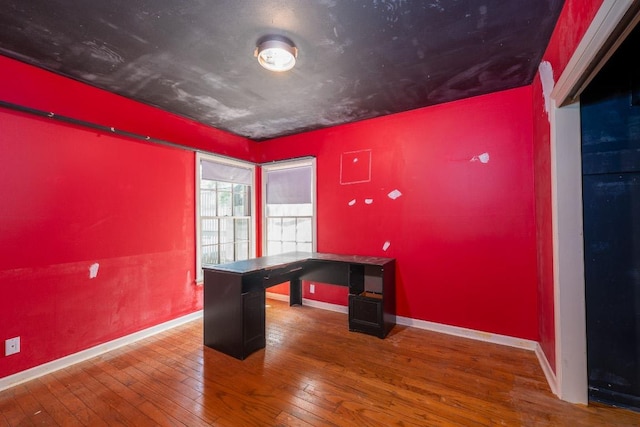 unfurnished office featuring baseboards and hardwood / wood-style floors