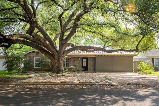ranch-style home featuring board and batten siding, brick siding, and fence