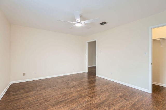 spare room featuring ceiling fan, visible vents, dark wood-style floors, and baseboards
