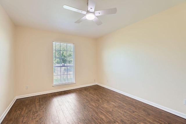 spare room with baseboards, dark wood-style flooring, and ceiling fan