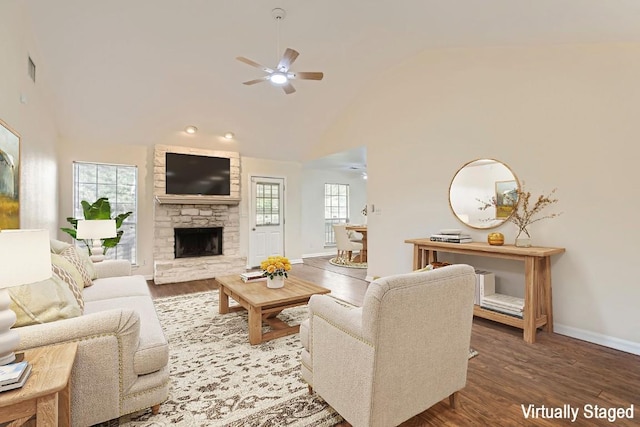 living room with baseboards, a ceiling fan, wood finished floors, and a stone fireplace