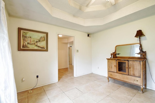 empty room featuring baseboards, a tray ceiling, visible vents, and light tile patterned floors