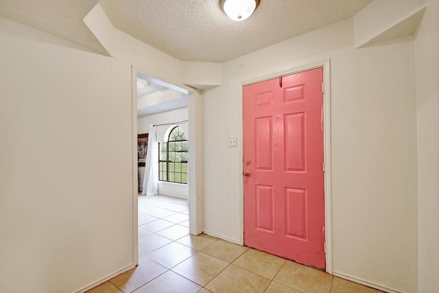 entrance foyer with baseboards, a textured ceiling, and light tile patterned flooring