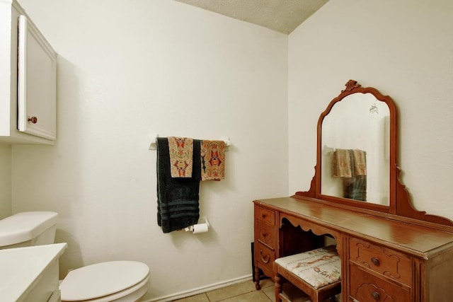 half bathroom with toilet, tile patterned floors, and vanity