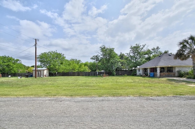 view of yard featuring fence, an outbuilding, and a storage unit