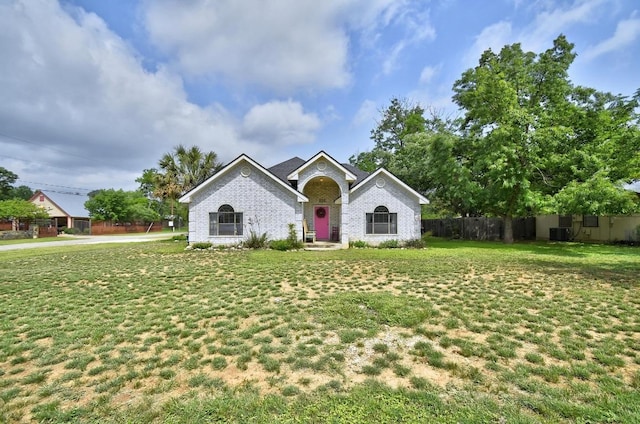 view of front of home with brick siding, fence, a front yard, and cooling unit