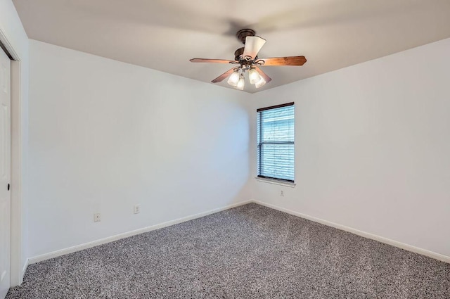 carpeted spare room featuring ceiling fan and baseboards