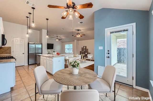 dining space with ceiling fan, visible vents, light tile patterned floors, and lofted ceiling