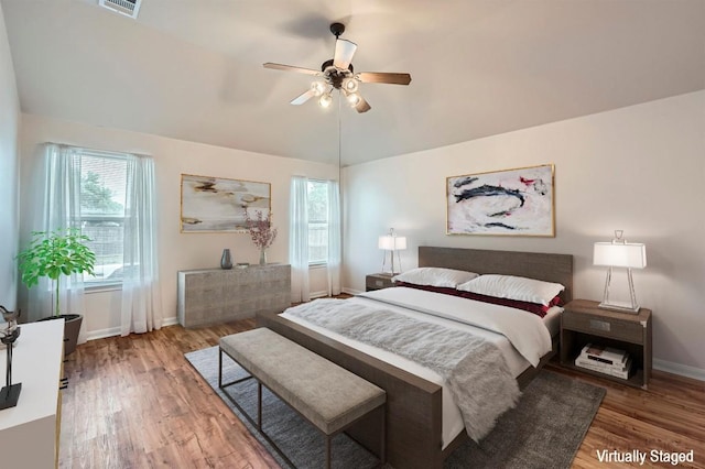 bedroom featuring baseboards, visible vents, multiple windows, and wood finished floors