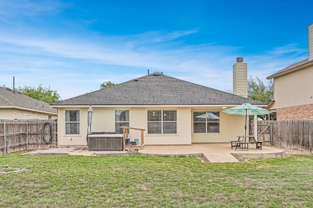 rear view of property featuring a patio, a shingled roof, a hot tub, and a fenced backyard