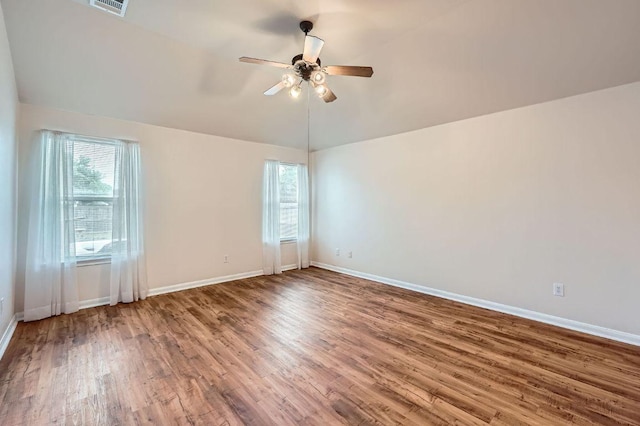 unfurnished room featuring baseboards, a ceiling fan, wood finished floors, and a wealth of natural light