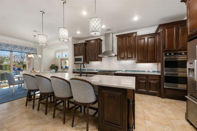 228 Cimarron Hills Trl E, Georgetown, TX 78628 - kitchen with wall chimney range hood, appliances with stainless steel finishes, crown molding, tasteful backsplash, and an island with sink