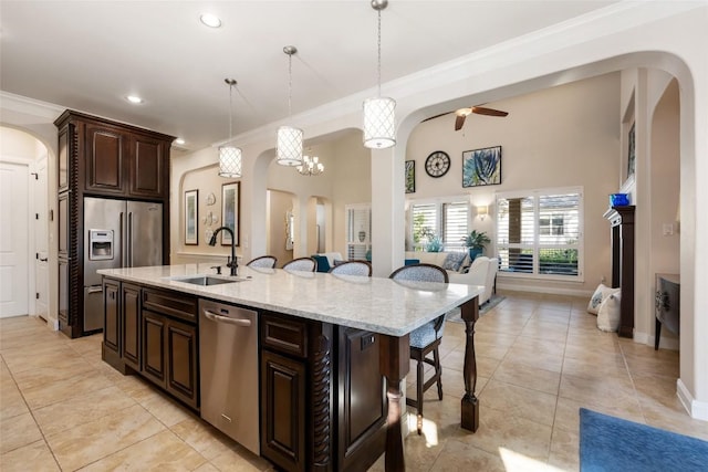 228 Cimarron Hills Trl E, Georgetown, TX 78628 - kitchen featuring appliances with stainless steel finishes, arched walkways, a kitchen breakfast bar, a ceiling fan, and ornamental molding