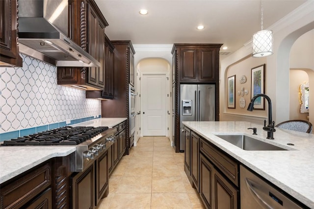 228 Cimarron Hills Trl E, Georgetown, TX 78628 - kitchen featuring wall chimney range hood, arched walkways, appliances with stainless steel finishes, dark brown cabinets, and decorative light fixtures