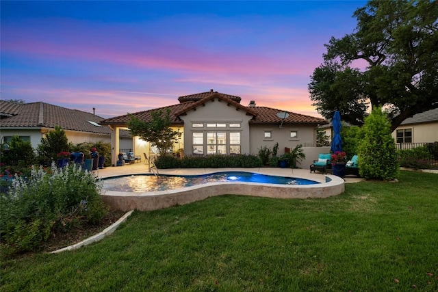 228 Cimarron Hills Trl E, Georgetown, TX 78628 - back of property at dusk featuring a tiled roof, a lawn, stucco siding, and a patio
