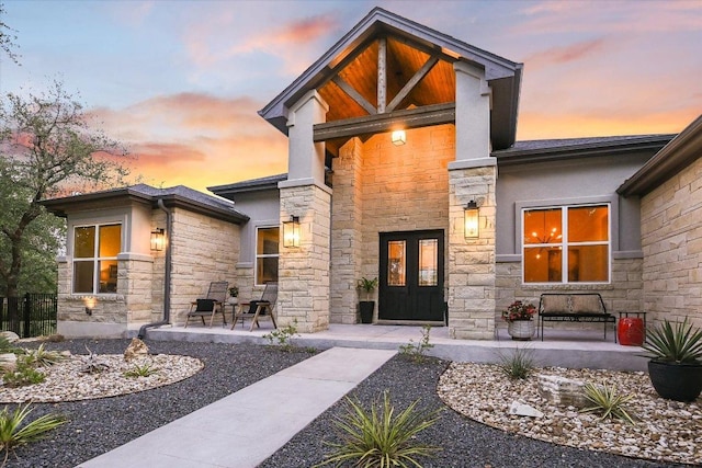 view of exterior entry featuring a porch, stucco siding, and stone siding