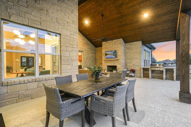 view of patio with an outdoor kitchen, area for grilling, an outdoor stone fireplace, outdoor dining area, and a ceiling fan