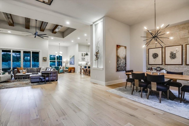 dining space featuring recessed lighting, beam ceiling, light wood finished floors, and a towering ceiling