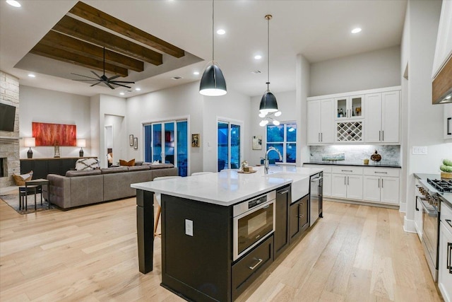1117 Eagle Point Dr, Georgetown, TX 78628 - kitchen featuring stainless steel microwave, a high ceiling, white cabinetry, light wood finished floors, and a ceiling fan